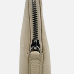 Close-up of a light beige pebbled leather clutch or wristlet with a black metal zipper, shown against a plain light gray background.