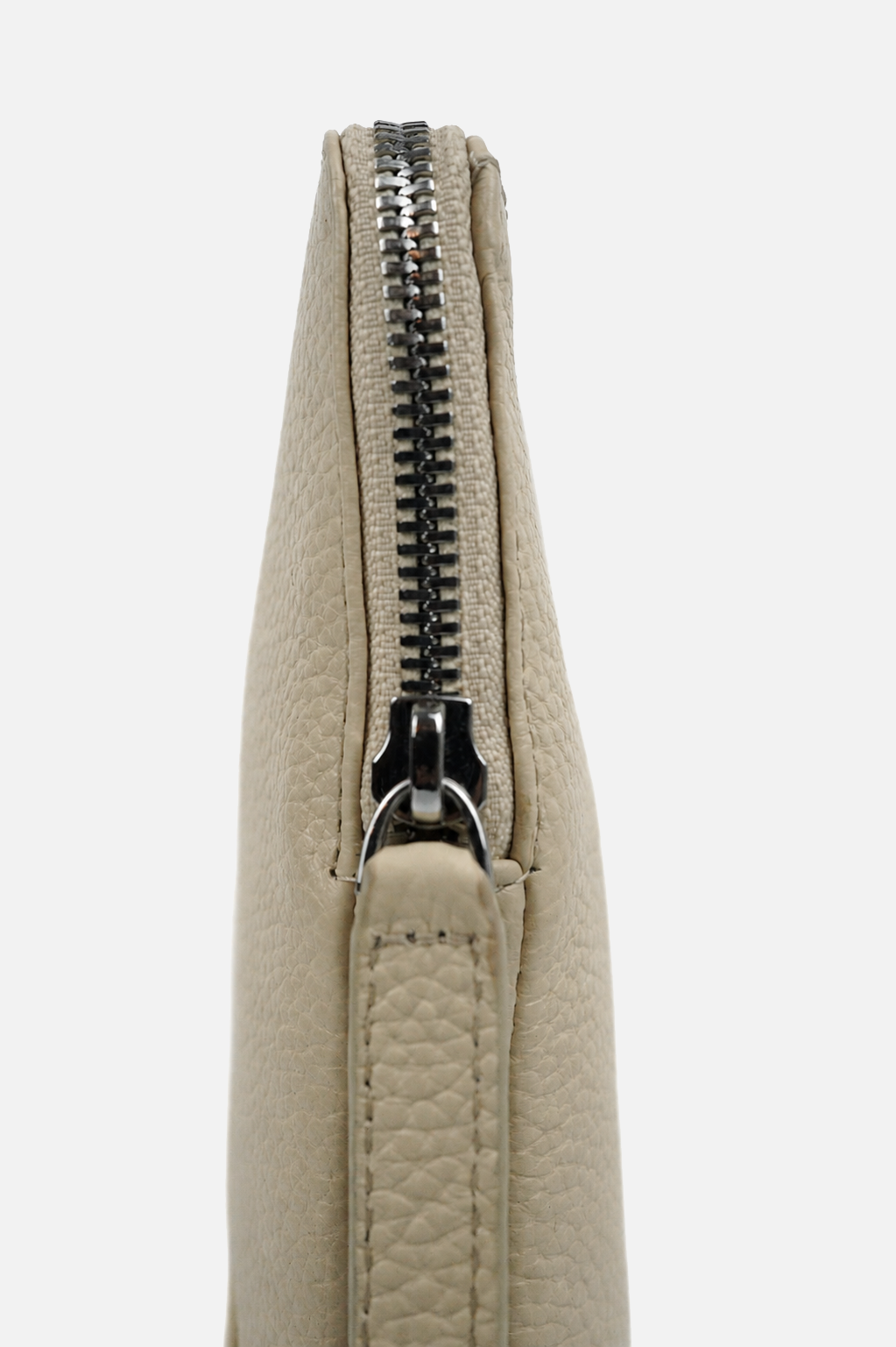 Close-up of a light beige pebbled leather clutch or wristlet with a black metal zipper, shown against a plain light gray background.